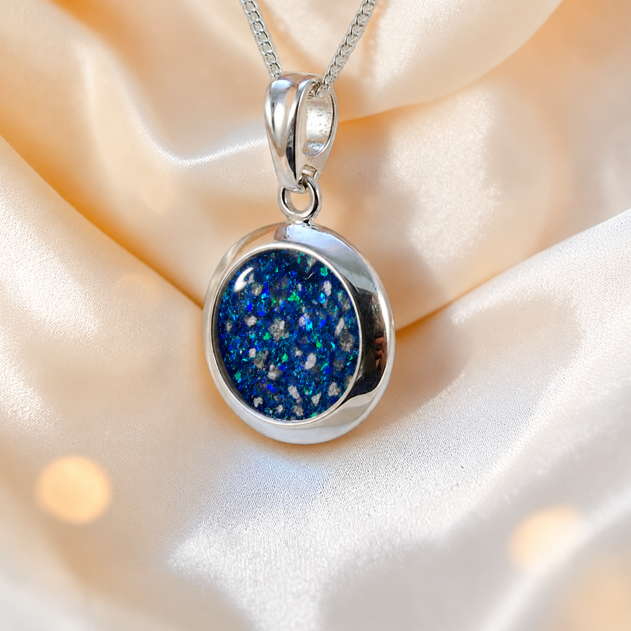 Altair round ashes pendant in sapphire glow, handcrafted in Lancashire UK
