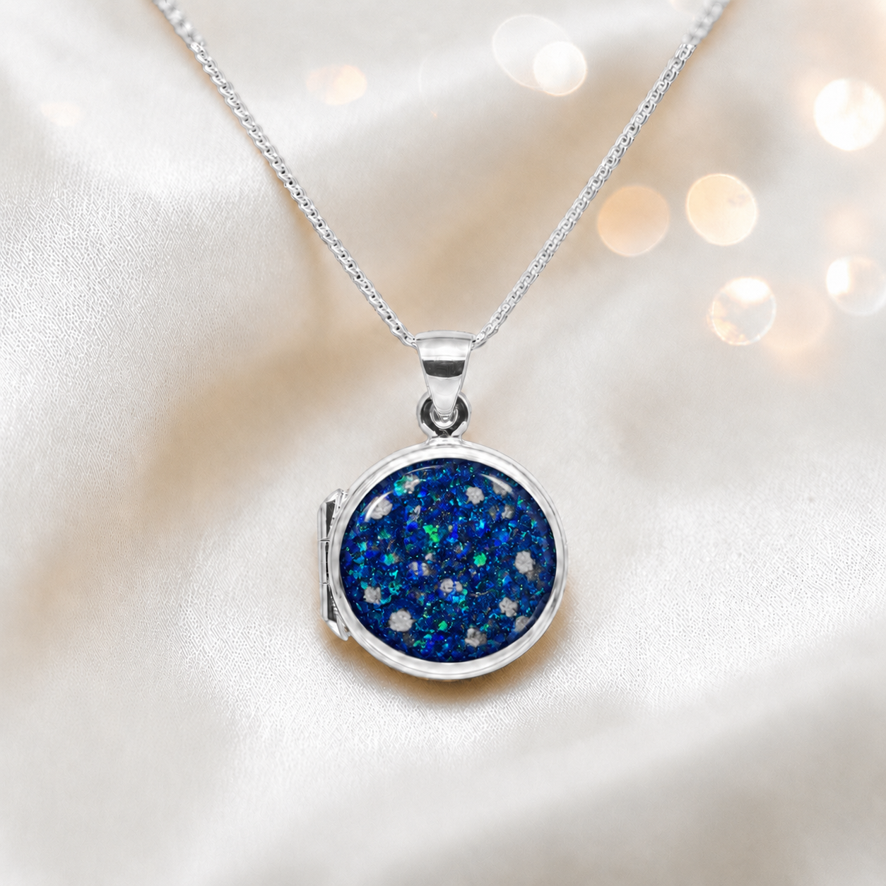 Electra round memorial locket in sterling silver, shown here in sapphire glow, handcrafted in Lancashire UK - by Keepsake Memorial Jewellery