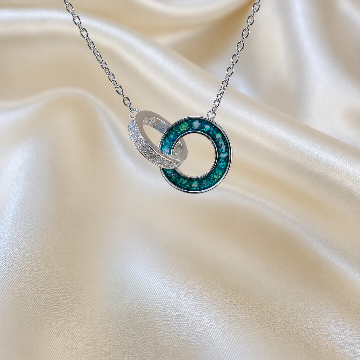 Eternal Embrace Pendant in 925 sterling silver — two interlocking rings with cubic zirconia in teal mist. Handcrafted memorial jewellery, made in Lancashire Uk -by Keepsake Memorial Jewellery