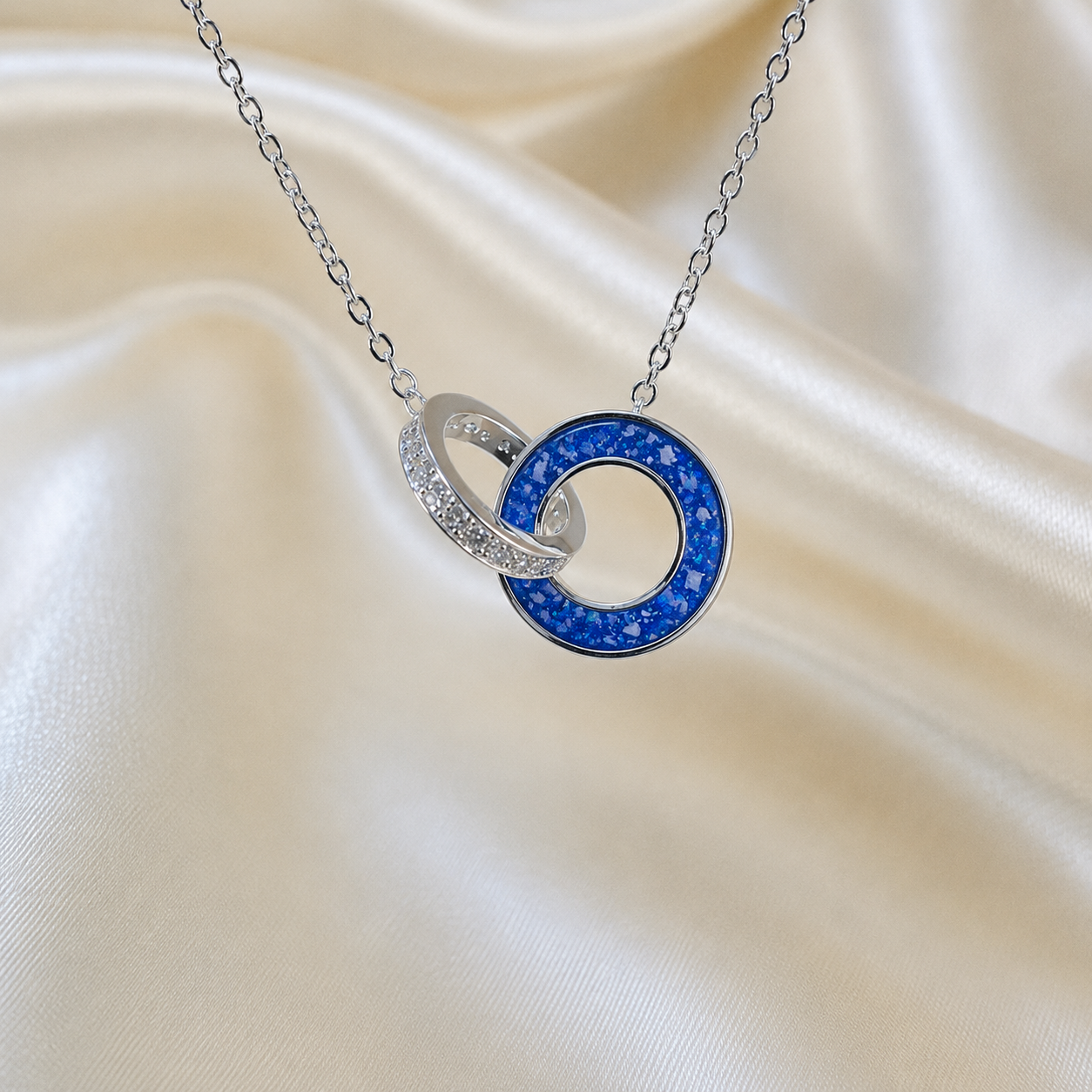 Eternal Embrace Pendant in 925 sterling silver — two interlocking rings with cubic zirconia in royal blue. Handcrafted memorial jewellery, made in Lancashire Uk -by Keepsake Memorial Jewellery