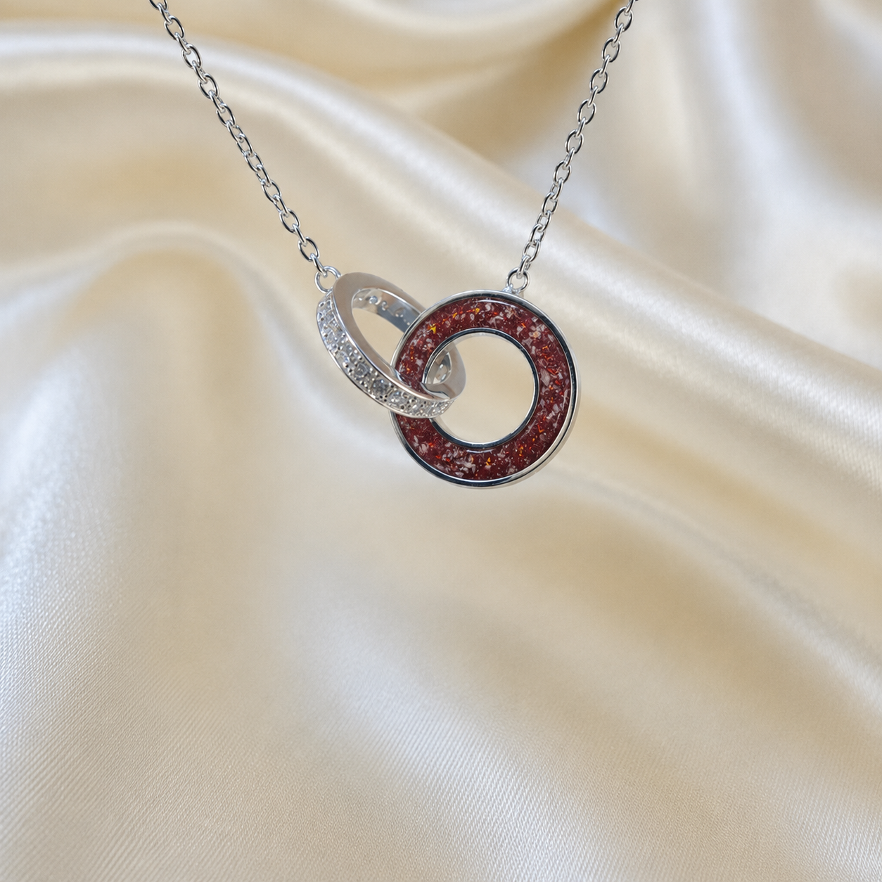 Eternal Embrace Pendant in 925 sterling silver — two interlocking rings with cubic zirconia in ruby red. Handcrafted memorial jewellery, made in Lancashire Uk -by Keepsake Memorial Jewellery