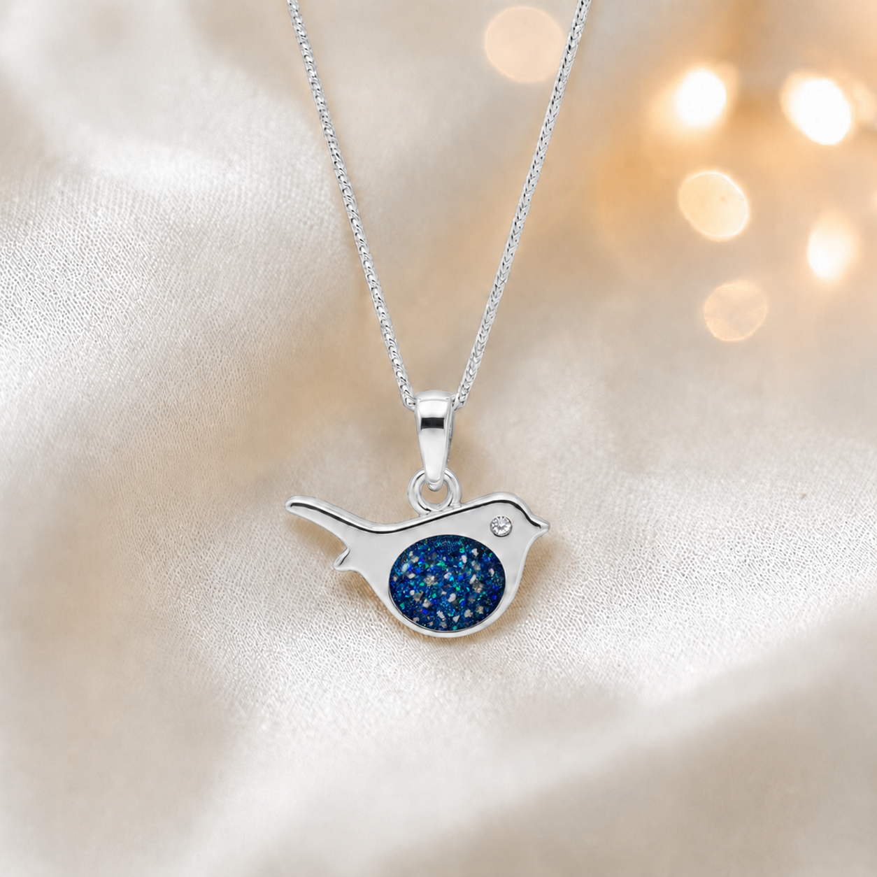 Robin bird shaped white gold memorial pendant in sapphire glow, handcrafted in Lancashire UK - by Keepsake Memorial Jewellery