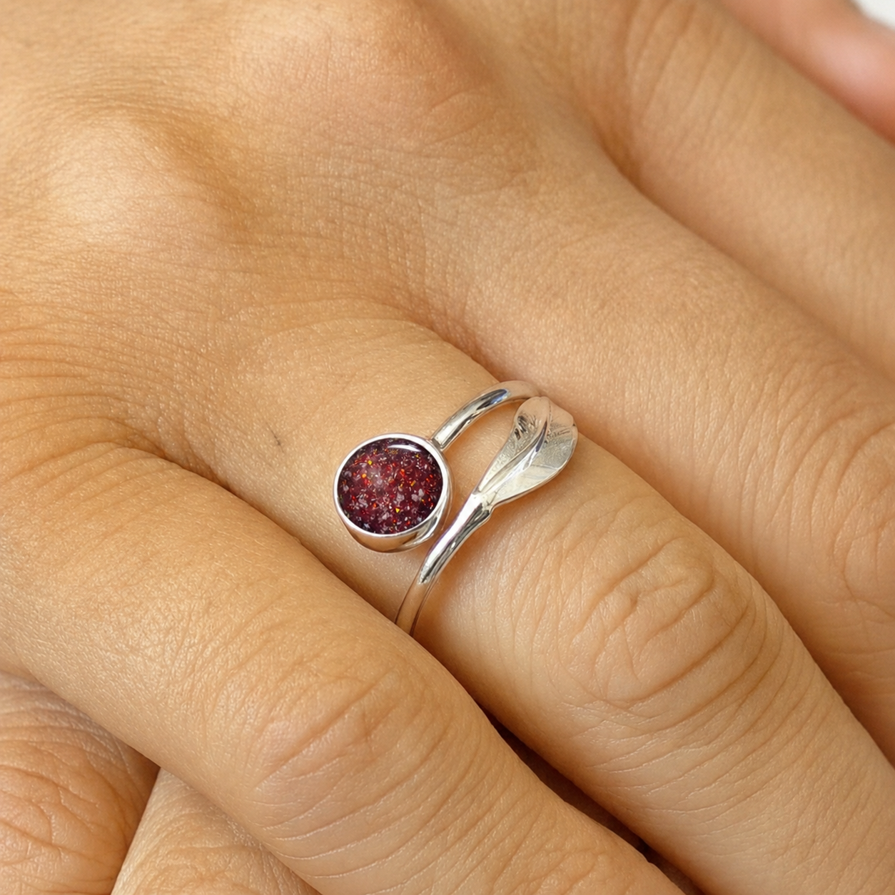 Feather Whisper Ring — silver feather ashes memorial ring, in ruby red, on models hand, handcrafted in Lancashire, UK
