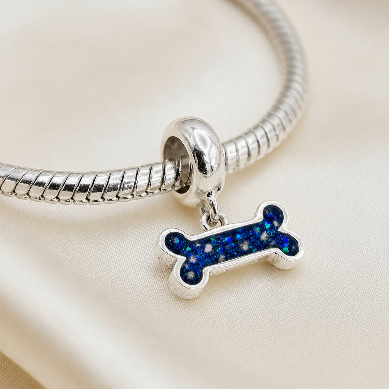 Milo silver dog bone ashes charm, in sapphire glow, handcrafted in Lancashire UK - by Keepsake Memorial Jewellery 