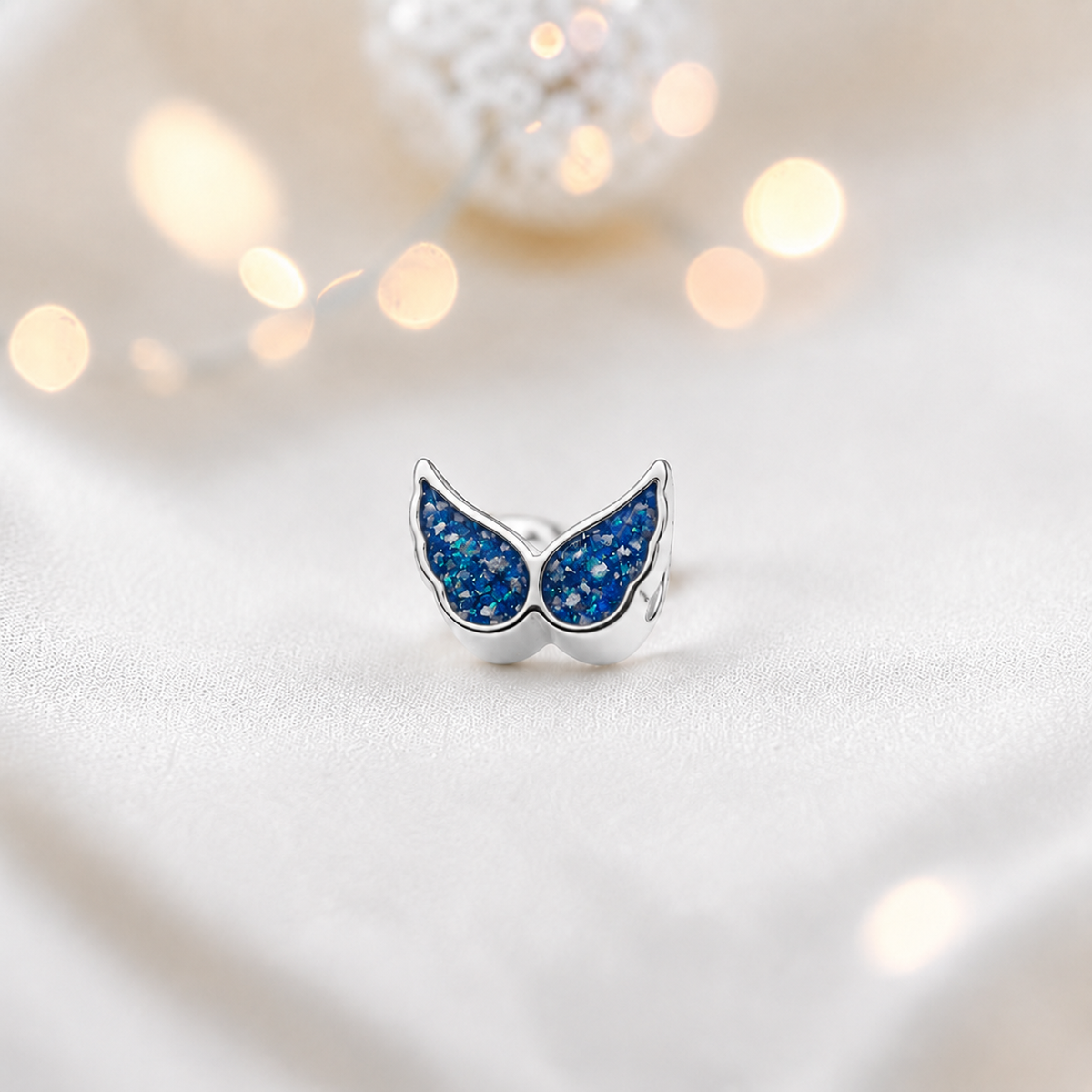 Sapphire glow sterling silver angel wing ashes memorial charm, handcrafted in Lancashire by keepsake memorial