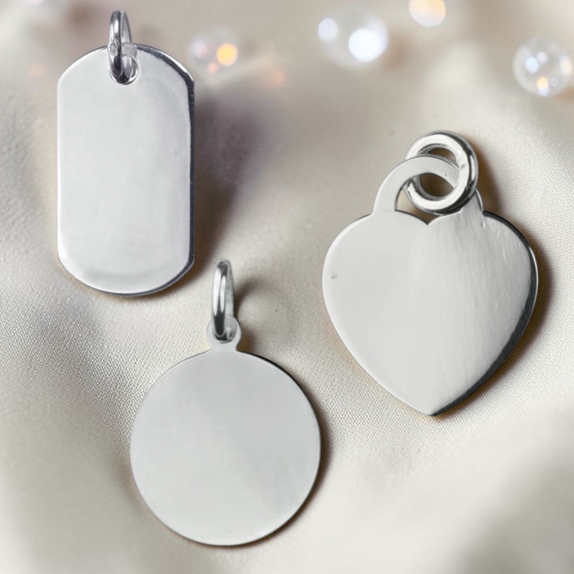 Three silver pendants on a light fabric background