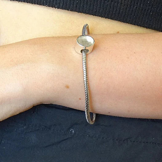silver oval ashes charm on wrist, handcrafted in uk