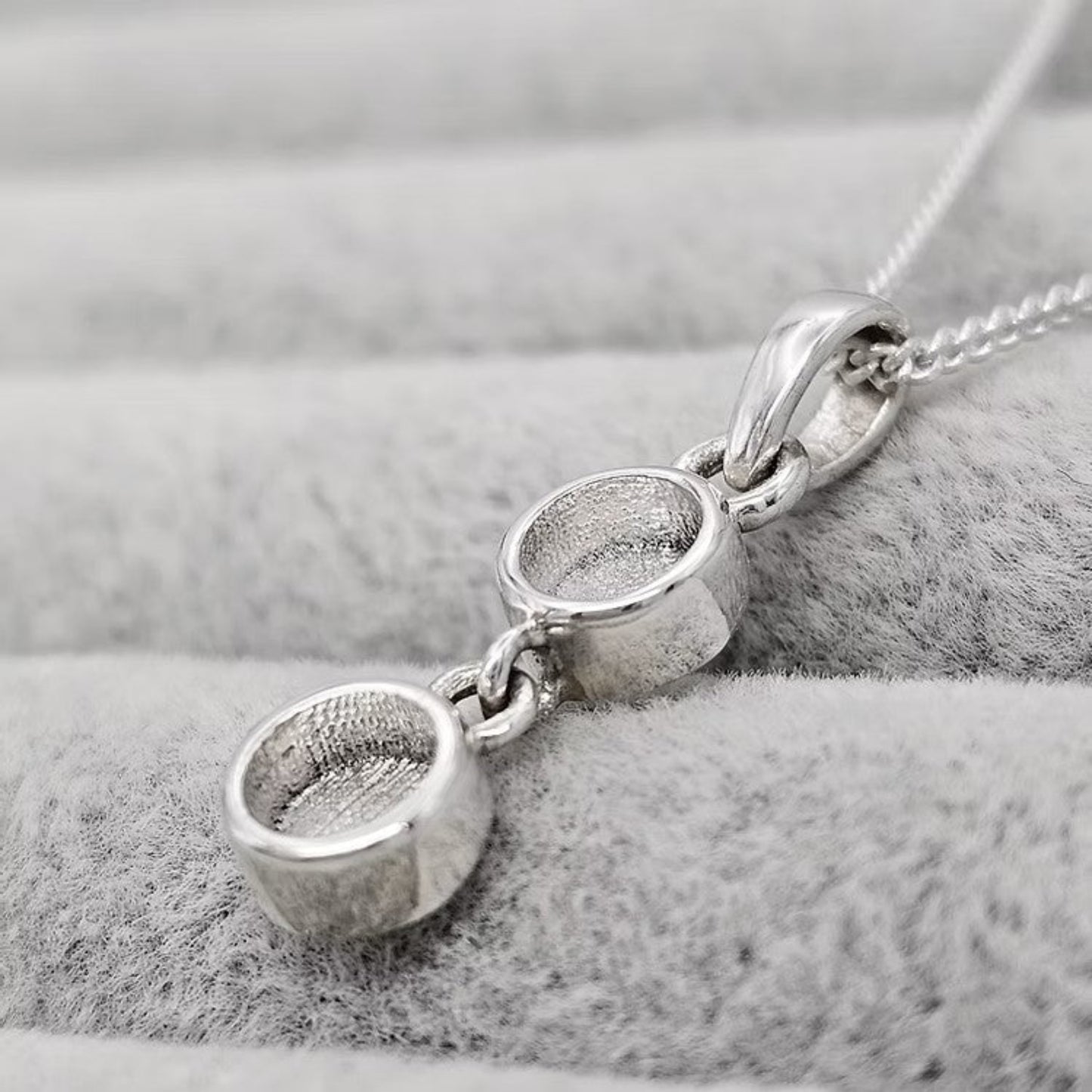 Silver necklace with three circular pendants on a soft gray background